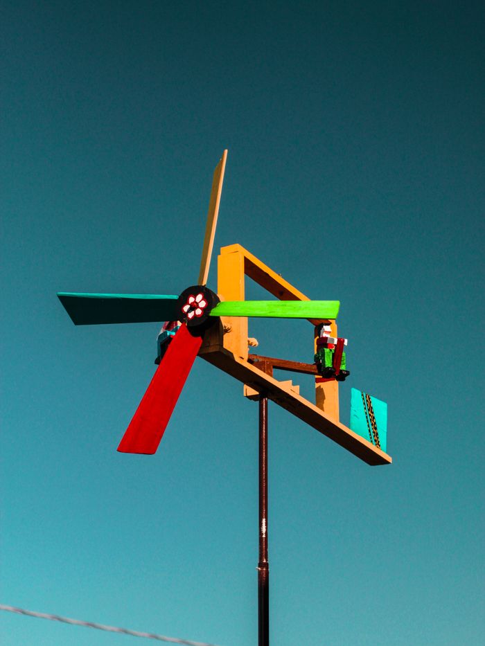 Vibrant handmade windmill with colorful blades set against a clear blue sky, symbolizing eco-friendly energy.